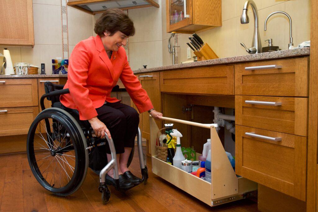 DAD Kitchen - Lady in wheelchair getting cleaner from under the sink