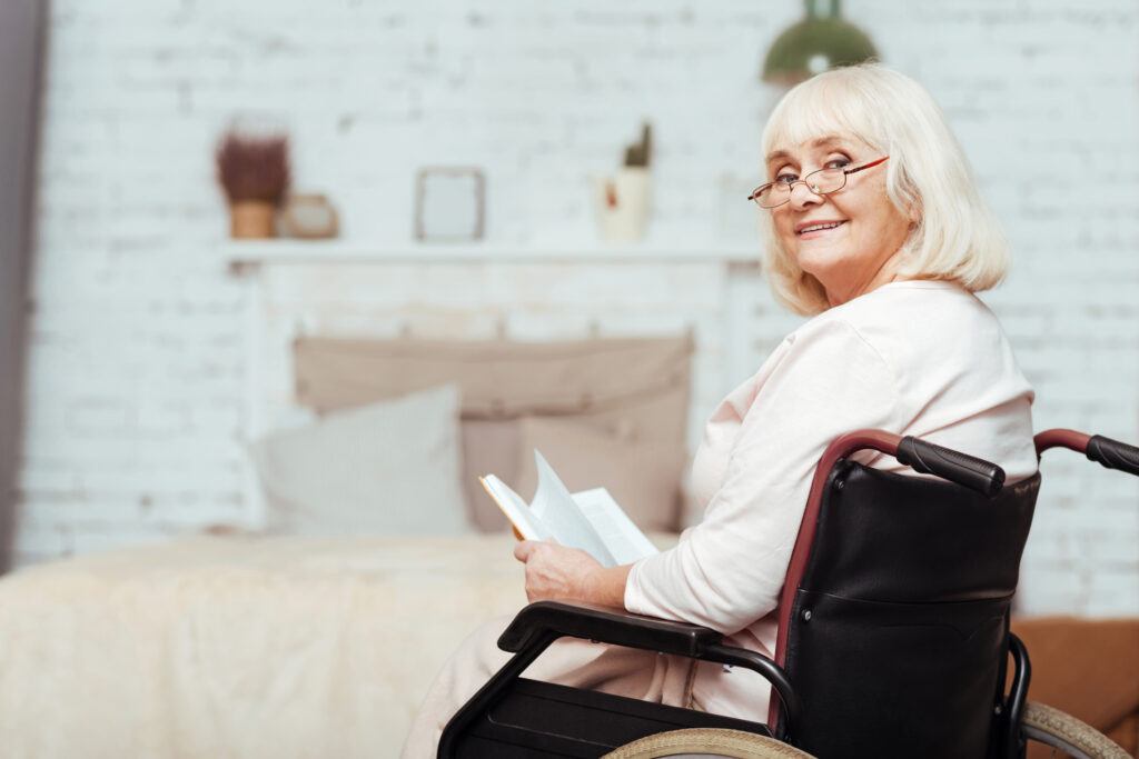 ADA Compliant Bedroom - lady reading in her bedroom in a wheelchair