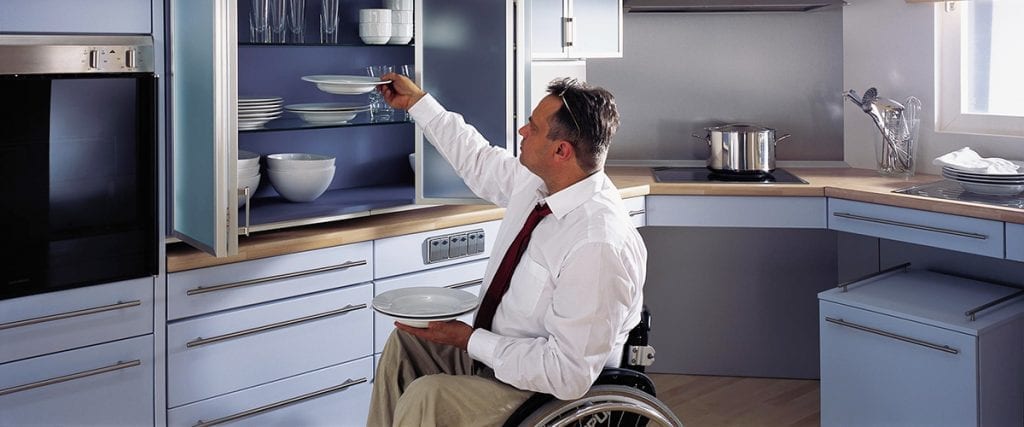 ADA Kitchen - Man in wheelchair reaching for a bowl