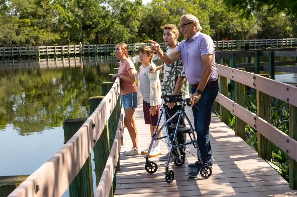 Family enjoying a walk by water with the da using a rollator walker