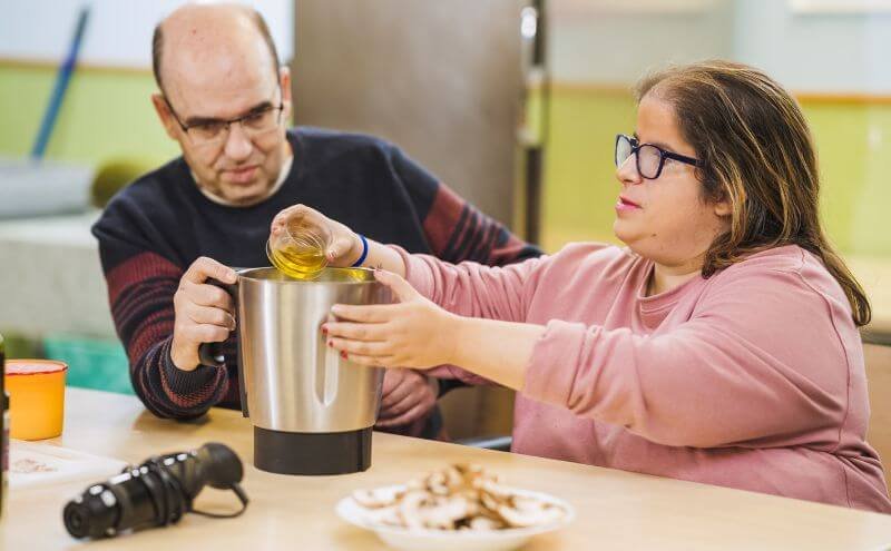 Disabled woman cooking with a friend