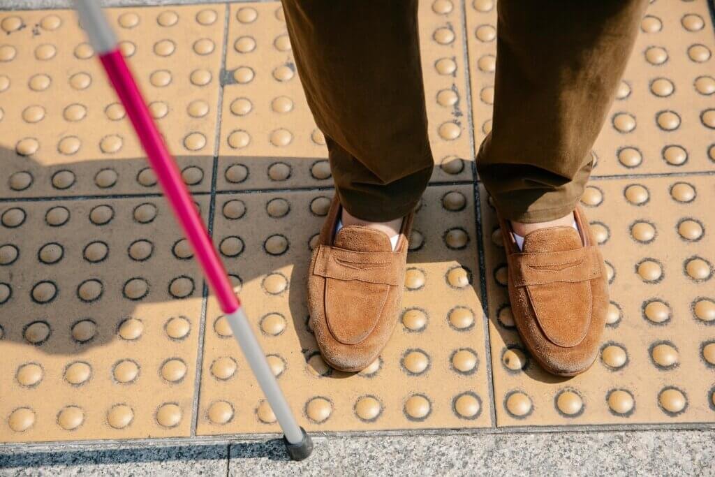 Gentleman using a cane waiting on a corner to cross the street