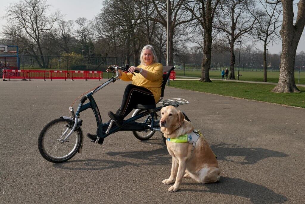 Lady riding a reclining bike with her dog