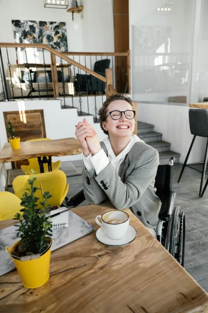 Lady sitting at a table enjoying here coffee in a wheelchair