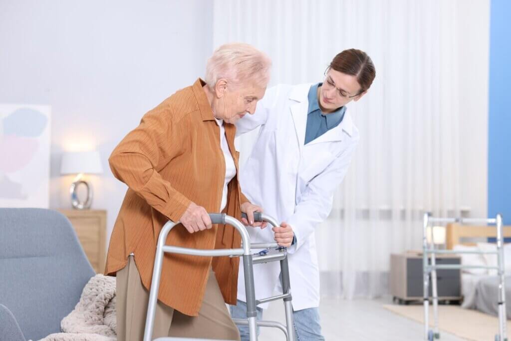 Older woman on a walker being helped by a caregiver