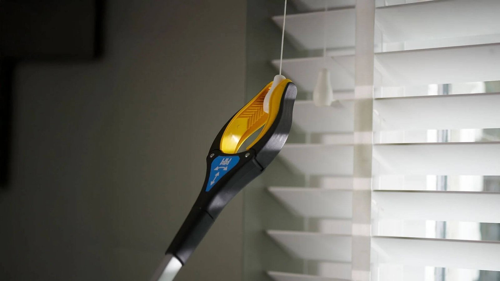 Someone using a reacher/grabber tool to open a blind