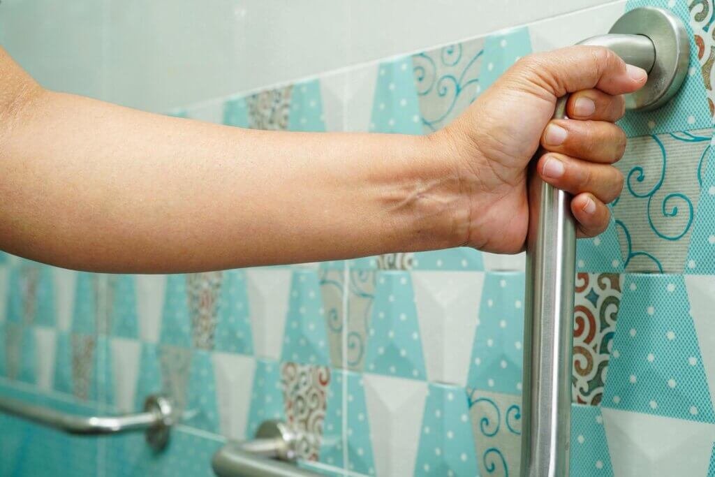 Someone using a grab bar in a shower for safety