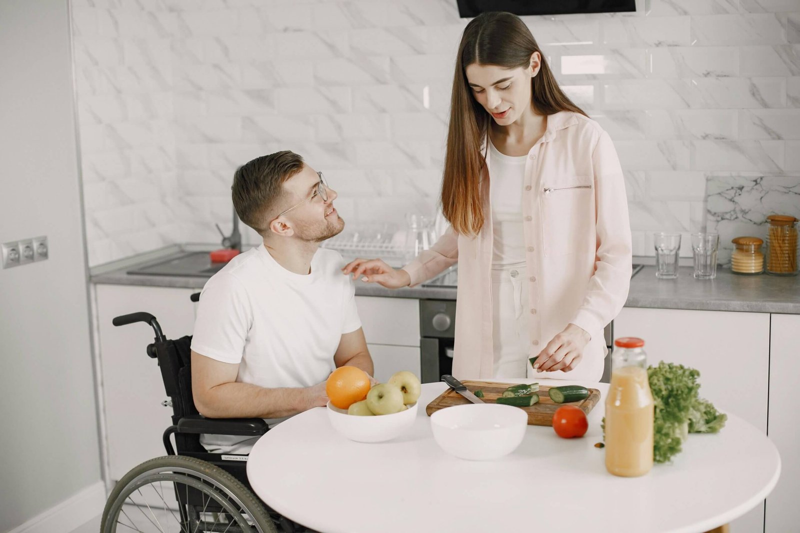 A couple one in a wheelchair making dinner in the kitchen