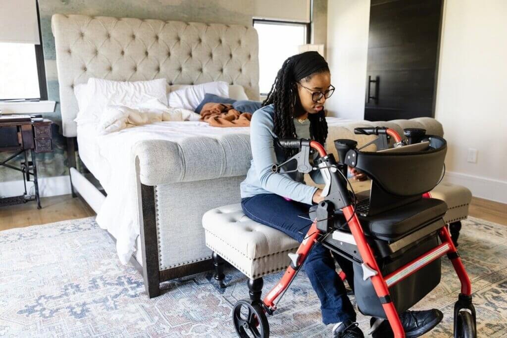 young woman using a walker in bedroom.
