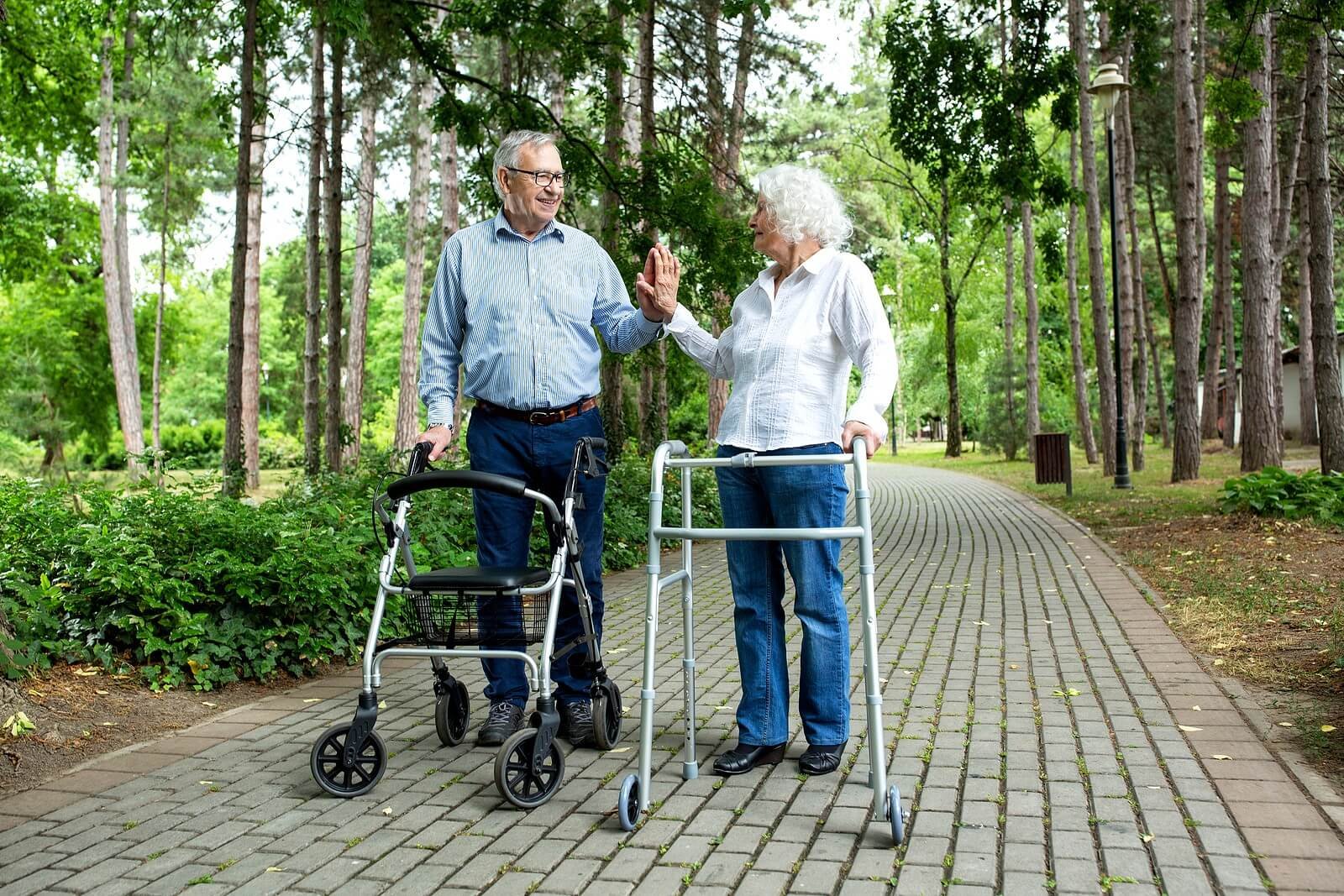 Two seniors greeting in a park using walkers