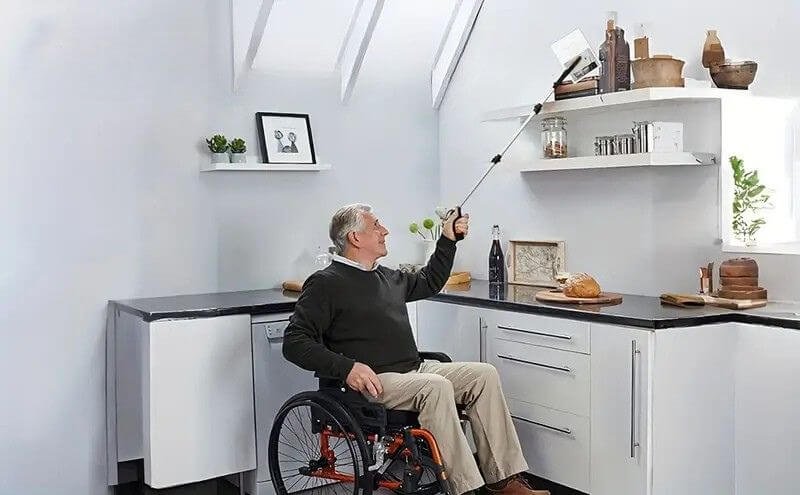 Man reaching for something off a shelf with a Kitchen Aids grabber tool