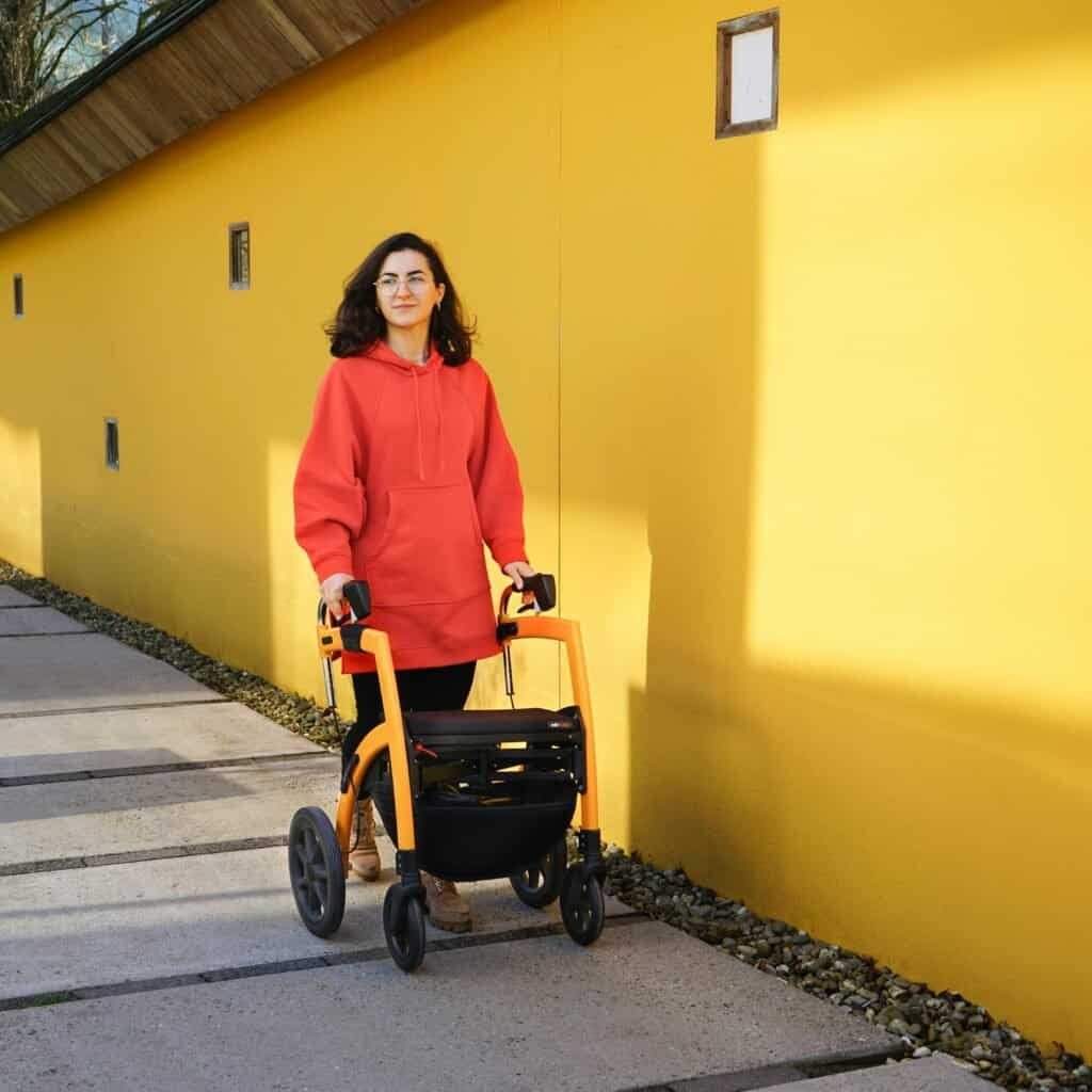 woman walking outdoors using rollator walker for mobility and independence