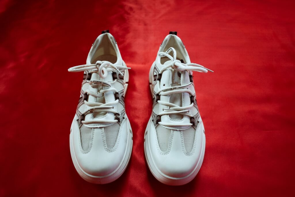 Pair of white supportive walking shoes on a red background designed to provide comfort, stability, and improved balance for safer walking.