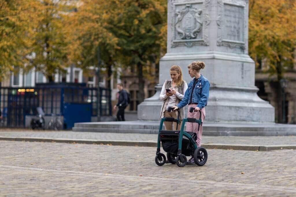 two young woman taking a walk one using a walker rollator