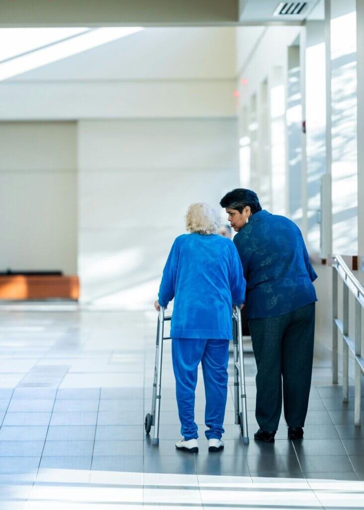 Paitent on a walker talking to her nurse
