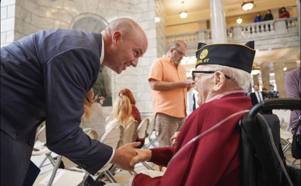 Ron's father, a World War II veteran, shakes hands with Utah Governor Spencer Cox during a ceremony honoring six World War II veterans over 100 years old.