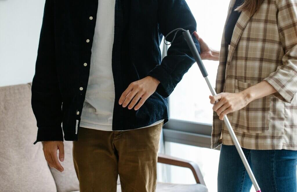 woman helping a man with a cane so he doesn't fall