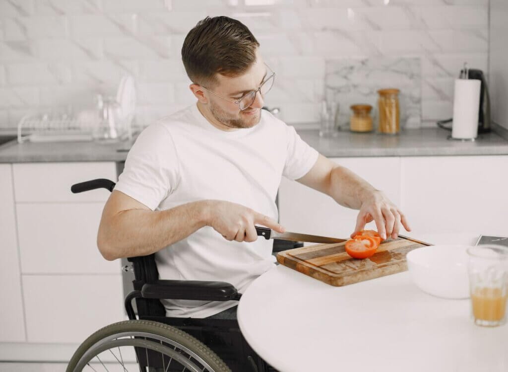 Adaptive Kitchen Aids -Wheelchair user preparing a meal in an accessible kitchen designed for independent living.