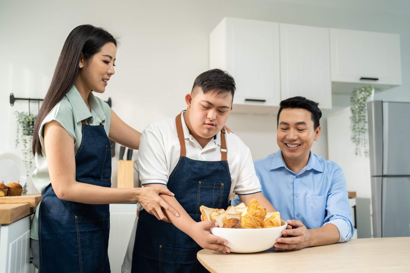 Young adult using adaptive cooking skills with family support in the kitchen.