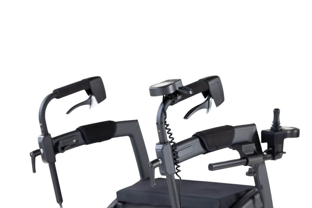 Close-up view of an upright rollator walker handle system featuring padded forearm supports, ergonomic hand brakes, adjustable height controls, joystick steering control, and a built-in display mounted above the handles against a light background.