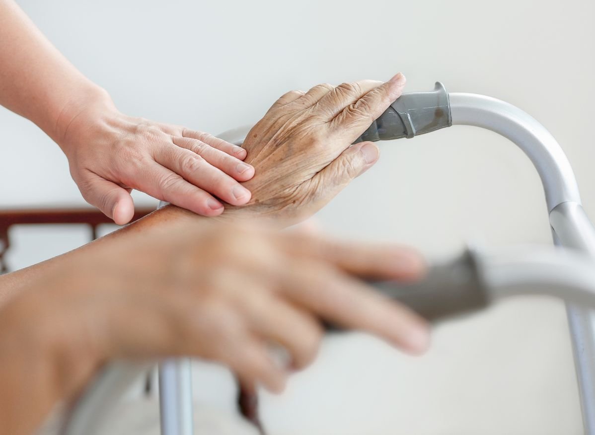 Caregiver assisting an older adult using a standard walker, demonstrating support, stability, and safe mobility.