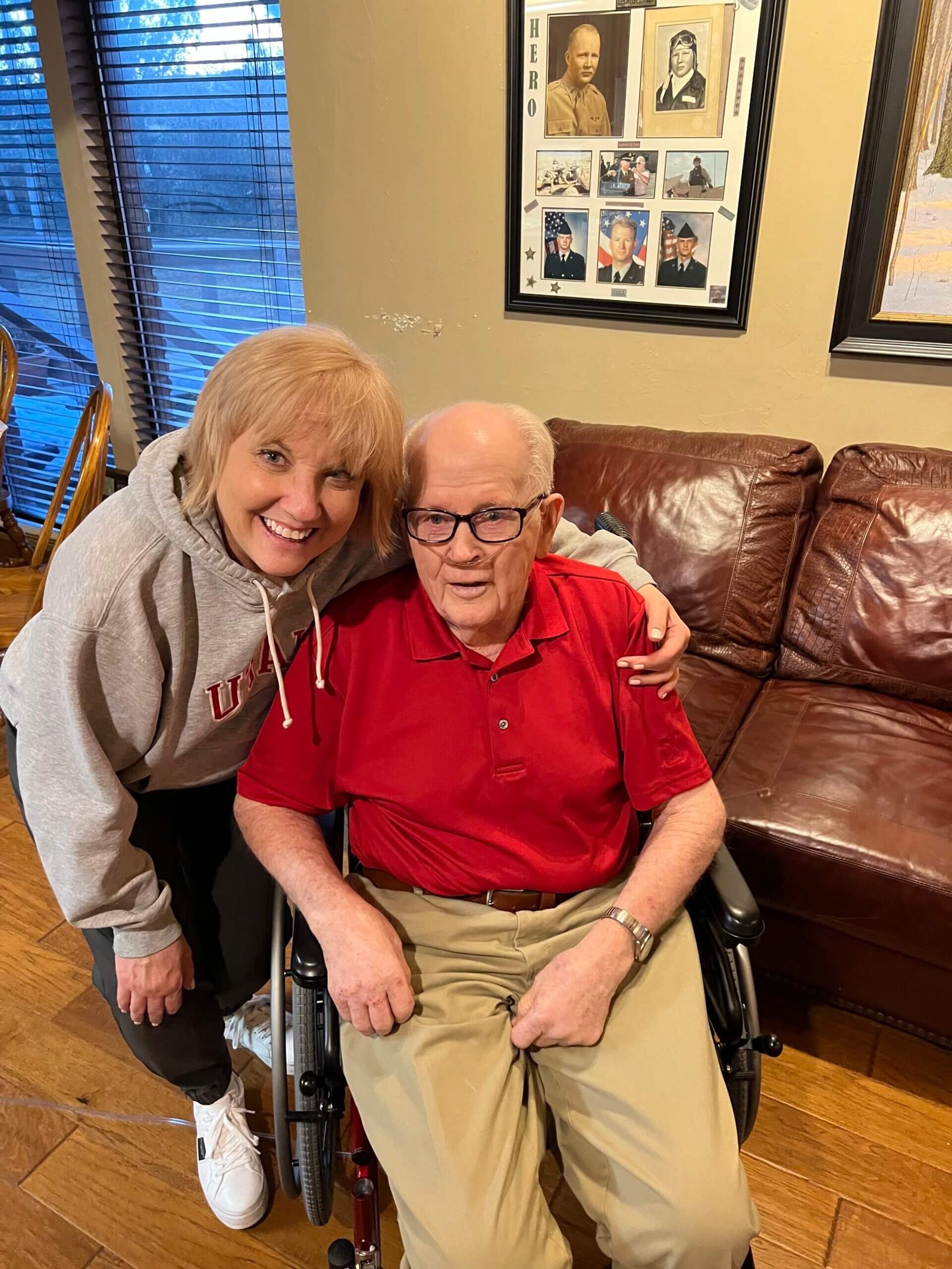 Ron's father sitting in his wheelchair with Joy, the daughter of his lifelong best friend, sharing a smile during a visit at home.