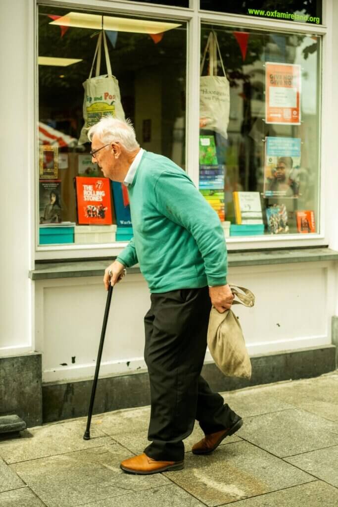 man taking a walk with bag groceries with a cane