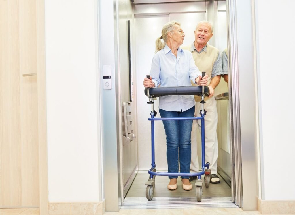 Does Medicare Cover Rollator Walkers?-Senior woman using a wheeled walker while exiting an elevator with assistance from a companion.