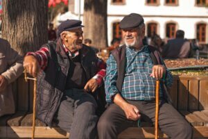 two men sitting on a beach both with cane looks like they have having a good time talking